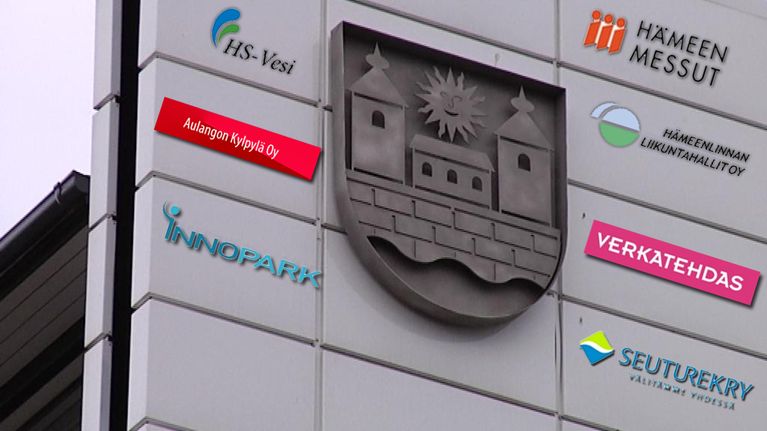 Hämeenlinnan vaakunan ympärillä kaupungintalon seinässä kaupungin yhtiöiden logoja