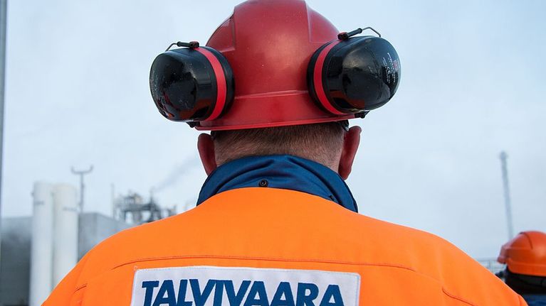 Talvivaaran työntekijä katselee tehtaan piippuja.