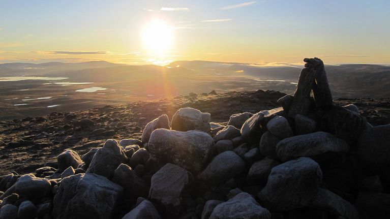 Aurinko nousee Saanan huipulla olevan seidan takaa
