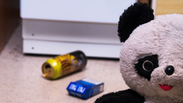 Lasten nalle, alkoholi juomatölkki ja tupakka aski lattialla