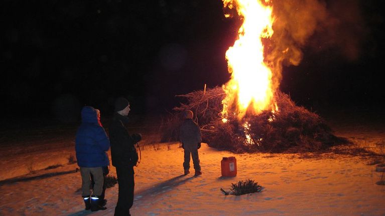 Kolme ihmistä katsoo pääsiäiskokkoa.
