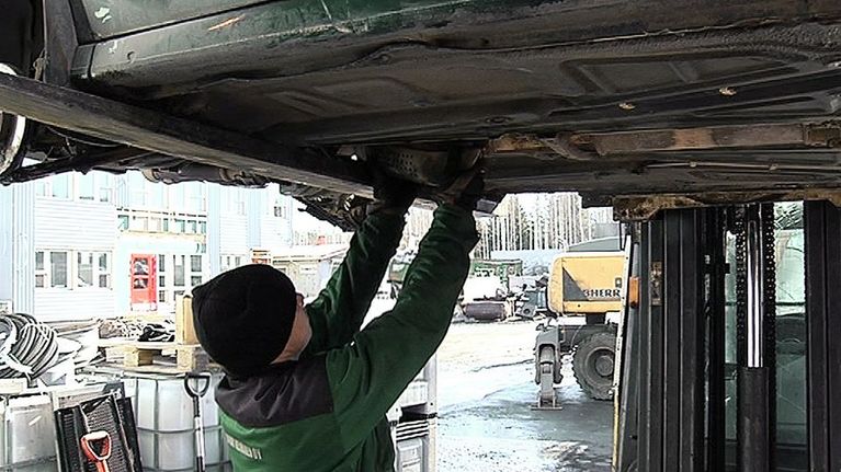 Vantaalaisen romuliikkeen Romu Keinäsen työntekijä irrottamassa katalysaattoria romutettavasta autosta.