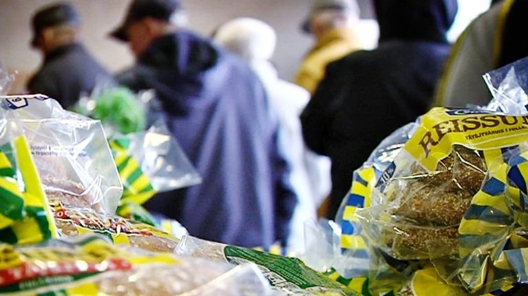 Ihmisiä jonottamassa ruokaa. Leipäpusseja etualalla.
