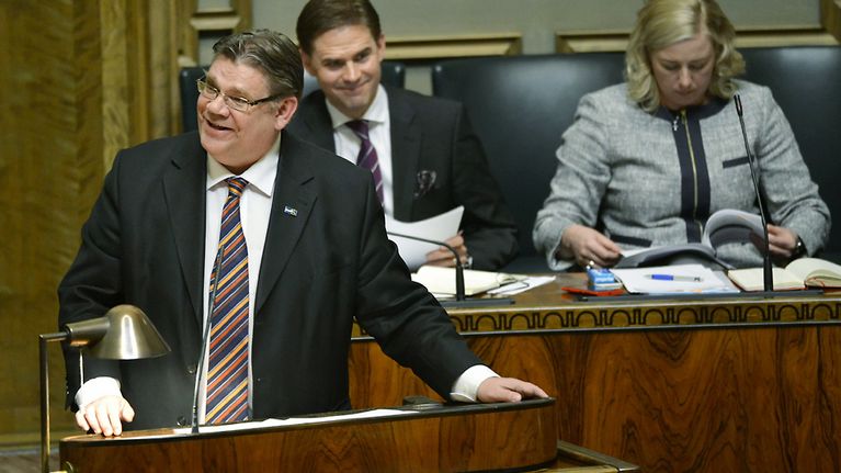 Perussuomalaisten puheenjohtaja Timo Soini pitämässä puheenvuoroaan eduskunnan täysistunnossa Helsingissä keskiviikkona 17. huhtikuuta 2013, takana ministeriaitiossa pääministeri Jyrki Katainen sekä valtiovarainministeri Jutta Urpilainen.