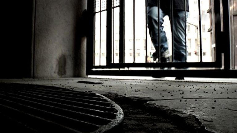 Anonyymi mies kävelee pimeään porttikäytävään.