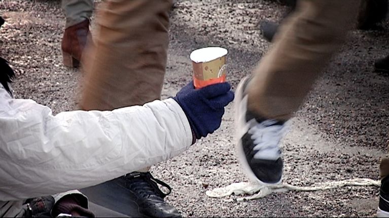 Nainen kerjää kadulla.