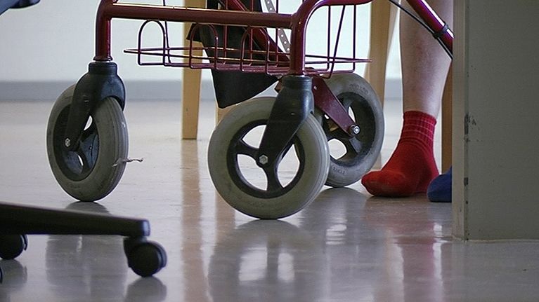 Henkilön jalat rollaattorin vierellä.