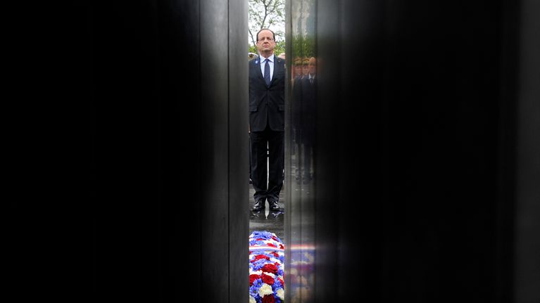 Francois Hollande kuvattuna muistomerkin välistä.