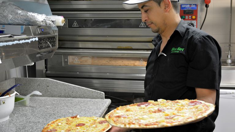 Mies tarjoilee pizzaa.