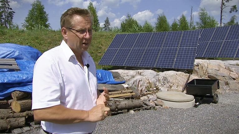 Mäntsäläläinen yrittäjä Markku Åberg pihalleen rakentamiensa aurinkopaneelien vierellä.
