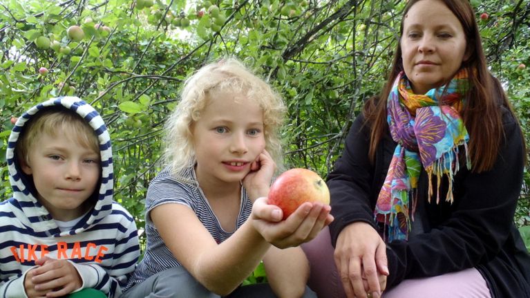 Oskari, Maisa ja Tarja Hiltunen-Ahonen esittelevät epäilyttävää omenaa. 