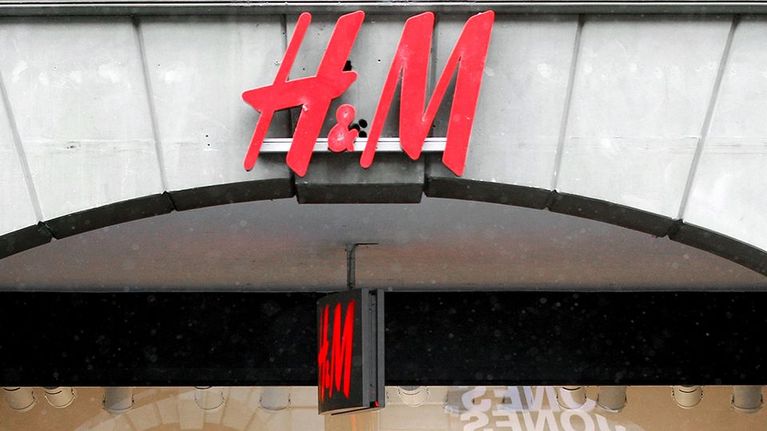 Hennes and Mauritziin kyltti vaateliikkeen oven yläpuolella.