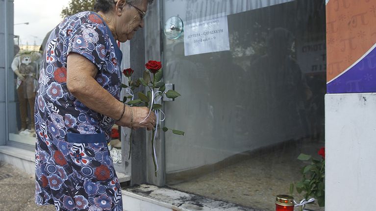 Nainen tuo kukkia paikalle Keratsinissa, jossa Pavlos Fyssas murhattiin.