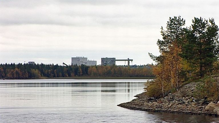 Kemijärven entinen sellutehdas kohoaa puiden takaa.