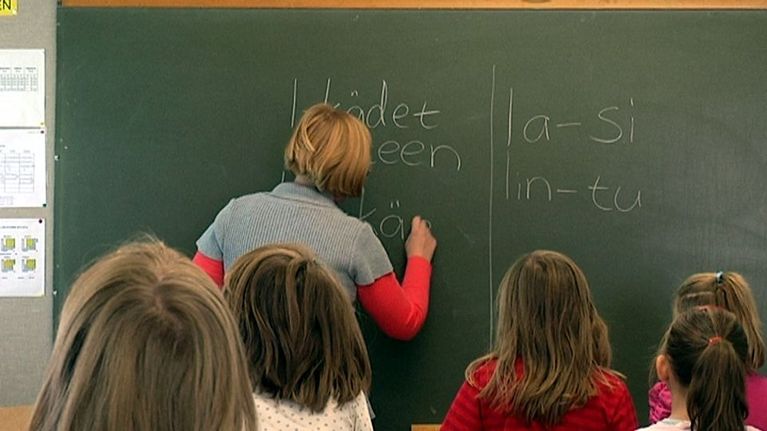 Opettaja kirjoittaa liitutaululle