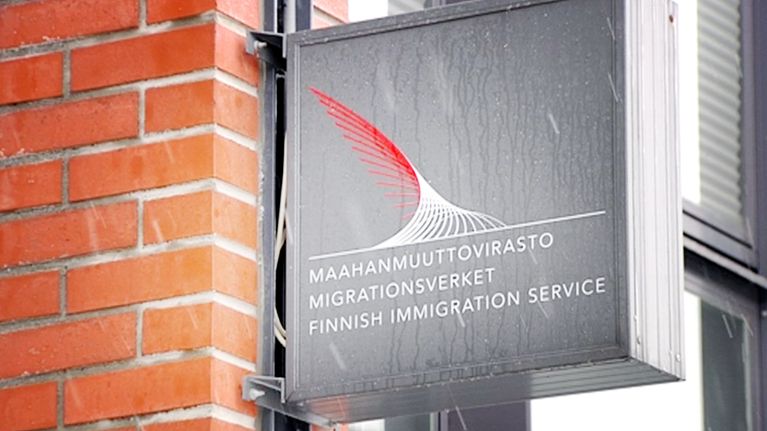 Maahanmuuttoviraston kyltti lumisateessa.