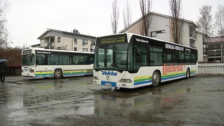 Kaksi bussia pysäköitynä hiekkakentällä