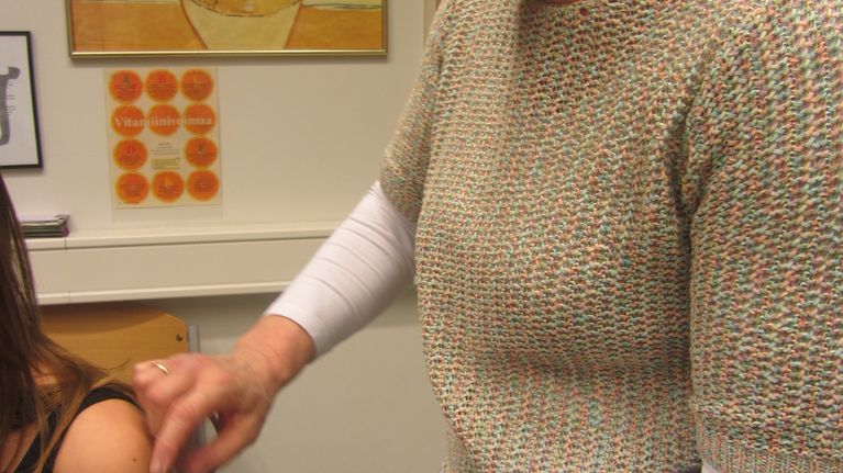 Terveydenhoitaja pistää rokotetta oppilaalle.