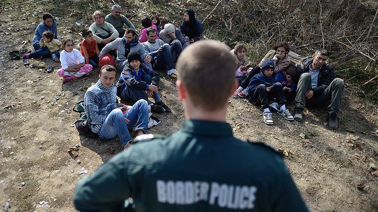 Bulgarialainen rajapoliisi vartioi kiinniotettujen syyrialaispakolaisten ryhmää Bulgarian ja Turkin rajalla lähellä Elhovon kaupunkia.