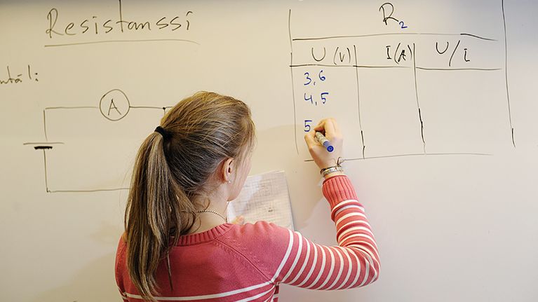 Koululainen tekee laskutoimitusta taululle.