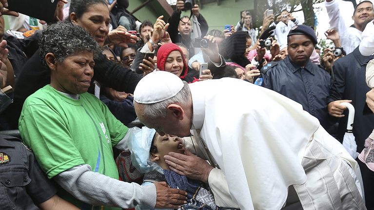 Paavi Franciscus siunaa lapsen vieraillessaan Varginhan favelassa Rio de Janeirossa.