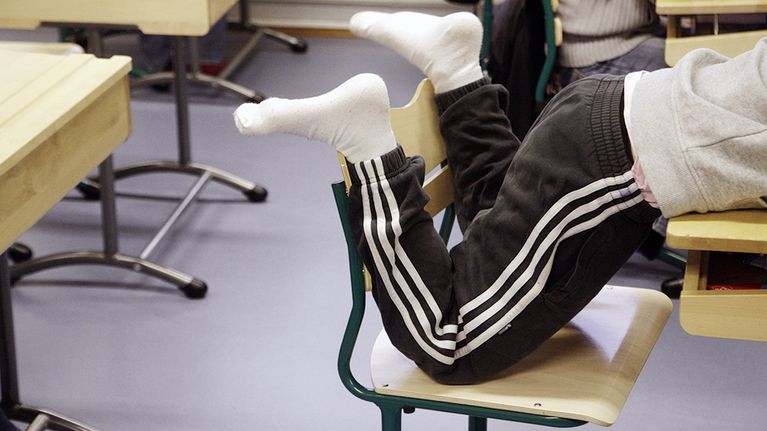 Koulualinen makaa pulpetin päällä koululuokassa.