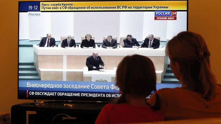 Äiti ja tytär katsovat televisiosta keskustelua, jossa Venäjän parlamentin ylähuone hyväksyy voimatoimet Ukrainassa.