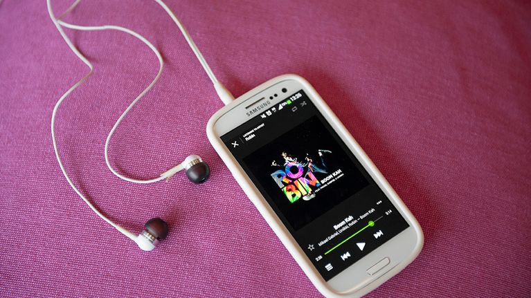 Samsungin kännykkä vaaleanpunaisella sohvalla.