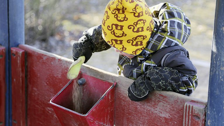 Pieni lapsi leikkii hiekalla leikkipuistossa.