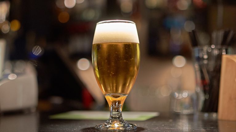 Beer in a stemmed glass on a bar.