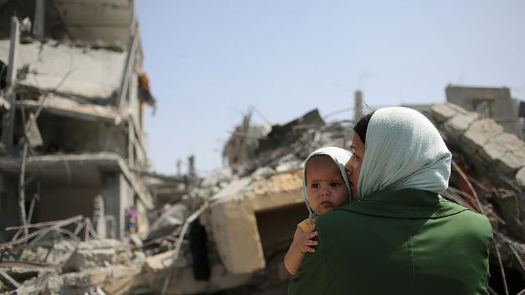 Palestiinalaisäiti katseli Israelin iskujen tuhoamien talojen raunioita Beit Hanunin kaupungissa Gazan kaistalla perjantaina.