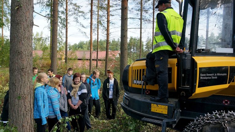 Opiskelijoita metsäkoneen äärellä.