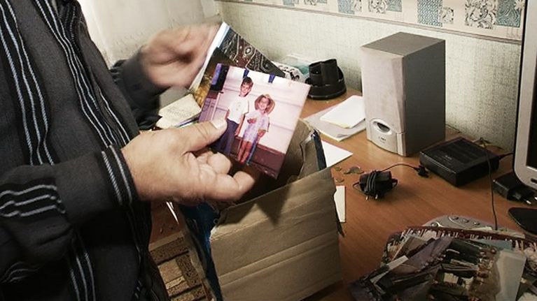 Mies esittelee valokuvia siepatusta pojastaan.