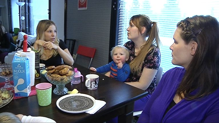 Äitejä ja lapsia kahvipöydässä.