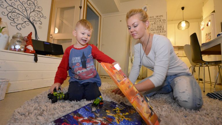 Sanna-Maria Mäkinen ja Rasmus-poika avaavat joulukalenterin luukkua.