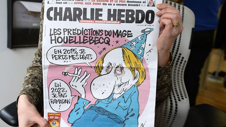 Henkilö näyttää ranskalaisen satiirisen sanomalehden Charlie Hebdon etusivua.
