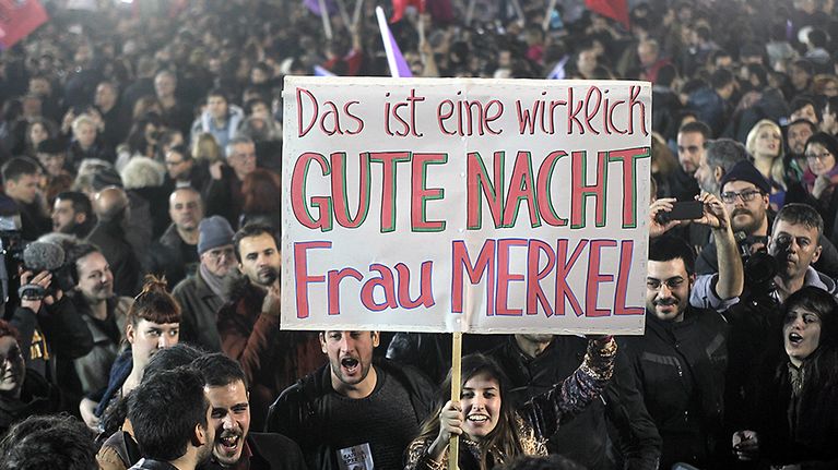 Syrizan kannattajat heiluttavat julistetta, jossa lukee "Hyvää yötä, rouva Merkel" saksaksi.