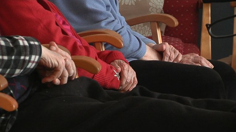 Vanhukset istuvat kädet sylissä vierekkäin. 