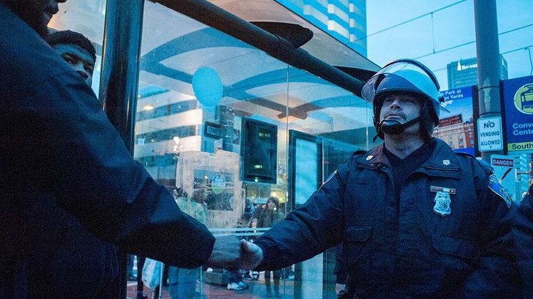 Mielenosoittaja ja poliisi kättelevät 25. huhtikuuta.