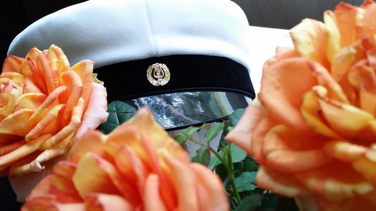 Kuvassa ylioppilaslakki ruusujen keskellä