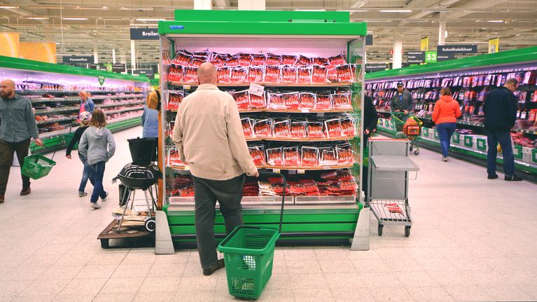 Asiakas katselee makkaroita kaupan kylmähyllyssä