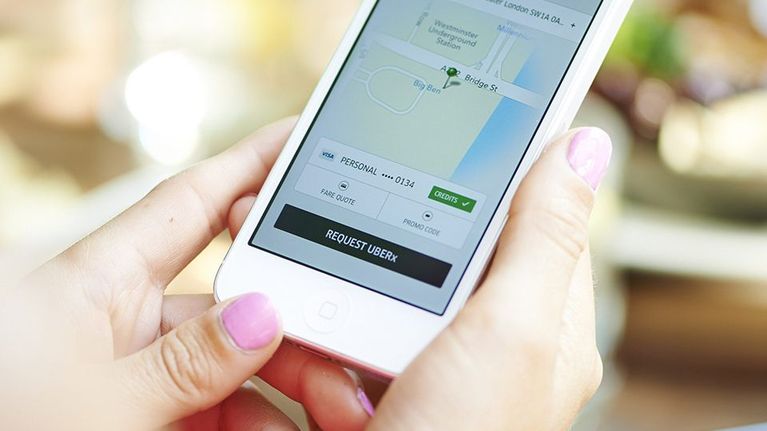 Henkilö käyttää Uber-sovellusta älypuhelimella.