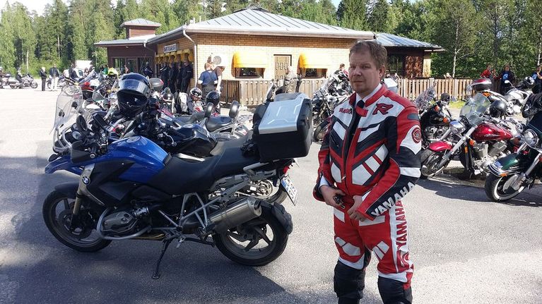 Motoristi moottoripyörän luona, taustalla muita pyöriä ja motoristeja
