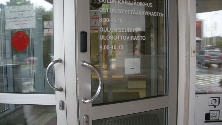 Oulun käräjäoikeuden ja syyttäjänviraston ulko-ovi hivenen avoinna.