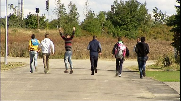 Nuoria miehiä tiellä kävelemässä poispäin.