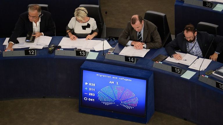 Neljä eurokansanedustajaa pöytänsä takana Strasbourgin parlamenttitalossa. Edessä näyttöruutu, jossa äänestystulos.