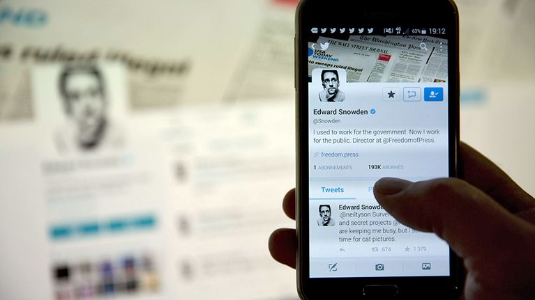 Puhelimen näytöllä ja takana olevalla tietokoneen ruudulla näkyy Edwardin Snowdenin Twitter-tili.