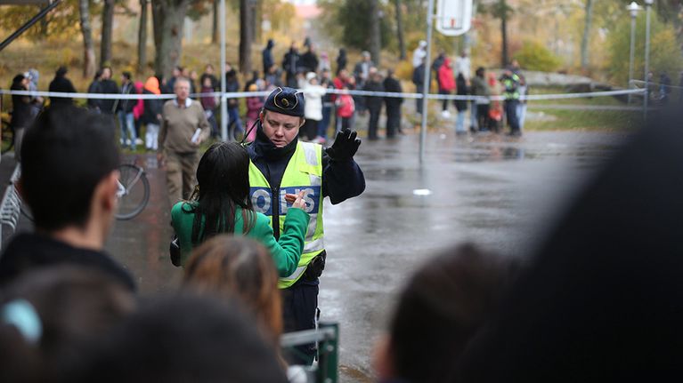 Poliisi keskustelemassa ihmisten kanssa Kronan-koulun edustalla Trollhättanissa torstaina.