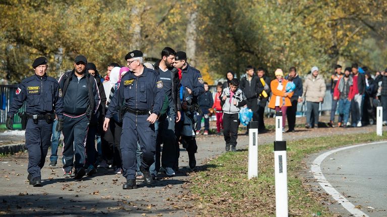 Kaksi poliisia marssii ihmisjoukon kärjessä syksyisellä tiellä. 