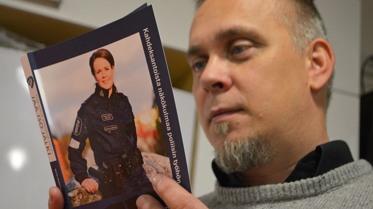 Poliisiviestinnän lehtori Marko Vesterbacka pitelee poliisiammattikorkeakoulun pääsykoekirjaa.